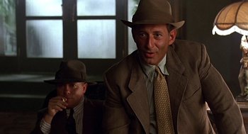 Movie still from “Barton Fink” (1991), directed by Joel Coen – A man in a suit and a hat sitting next to another man in a hat; Close Up shot, Low angle