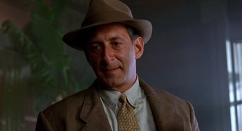 Movie still from “Barton Fink” (1991), directed by Joel Coen – A person wearing a suit and hat; Close Up shot, Low angle