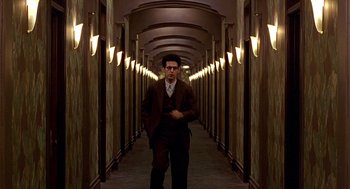 Movie still from “Barton Fink” (1991), directed by Joel Coen – A man in a suit and tie standing in a hallway; Wide shot, Low angle