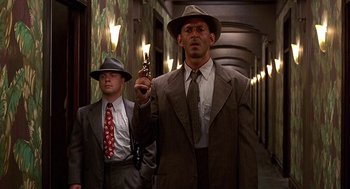 Movie still from “Barton Fink” (1991), directed by Joel Coen – A man holding a gun while standing next to another man; Medium shot, Low angle