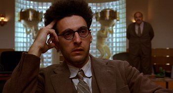 Movie still from “Barton Fink” (1991), directed by Joel Coen – A man in a suit and tie holding his hand to his head; Close Up shot, Low angle