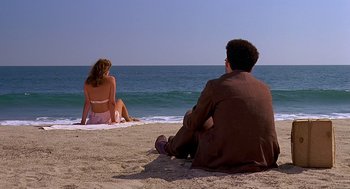 Movie still from “Barton Fink” (1991), directed by Joel Coen – A man and a woman sitting on the beach looking out at the ocean; Wide shot, High angle