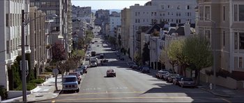 Movie still from “Basic Instinct” (1992), directed by Paul Verhoeven – Cars driving down a street lined with tall buildings; Extreme Wide shot, High angle