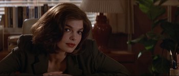 Movie still from “Basic Instinct” (1992), directed by Paul Verhoeven – A woman sitting in front of a lamp in a living room; Close Up shot, Over the shoulder angle