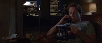 Movie still from “Basic Instinct” (1992), directed by Paul Verhoeven – A man sitting on the floor talking on a phone; Medium shot, High angle