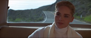 Movie still from “Basic Instinct” (1992), directed by Paul Verhoeven – A woman sitting in the back seat of a car; Close Up shot, Over the shoulder angle