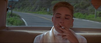 Movie still from “Basic Instinct” (1992), directed by Paul Verhoeven – A woman smoking a cigarette while sitting in a car; Close Up shot, Low angle