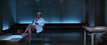 Movie still from “Basic Instinct” (1992), directed by Paul Verhoeven – A woman sitting on a chair looking at her cell phone; Wide shot, Low angle
