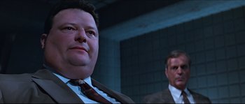 Movie still from “Basic Instinct” (1992), directed by Paul Verhoeven – A man in a suit and tie next to another man in a suit and tie; Close Up shot, Low angle