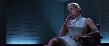 Movie still from “Basic Instinct” (1992), directed by Paul Verhoeven – A woman smoking a cigarette while holding a cell phone; Medium shot, Low angle