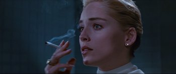 Movie still from “Basic Instinct” (1992), directed by Paul Verhoeven – A woman smoking a cigarette in front of a mirror; Close Up shot, Low angle