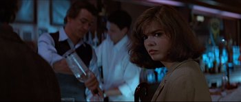 Movie still from “Basic Instinct” (1992), directed by Paul Verhoeven – A woman in a brown dress is in a bar; Close Up shot, Over the shoulder angle