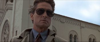 Movie still from “Basic Instinct” (1992), directed by Paul Verhoeven – A person wearing a suit and sunglasses; Close Up shot, Low angle