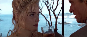 Movie still from “Basic Instinct” (1992), directed by Paul Verhoeven – A person holding a drink near a tree; Close Up shot, Over the shoulder angle