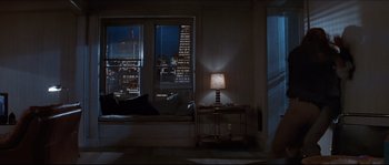 Movie still from “Basic Instinct” (1992), directed by Paul Verhoeven – A lamp is lit up in a dimly - lit room; Wide shot, High angle