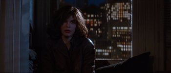 Movie still from “Basic Instinct” (1992), directed by Paul Verhoeven – A woman sitting in front of a window at night; Medium shot, Over the shoulder angle