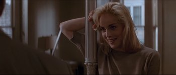 Movie still from “Basic Instinct” (1992), directed by Paul Verhoeven – A woman leaning against a pole in a room; Close Up shot, Over the shoulder angle