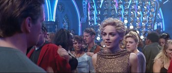 Movie still from “Basic Instinct” (1992), directed by Paul Verhoeven – A group of people standing in a room with lights in the background; Medium shot, Over the shoulder angle