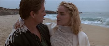 Movie still from “Basic Instinct” (1992), directed by Paul Verhoeven – A man and a woman standing next to each other on the beach; Close Up shot, Low angle