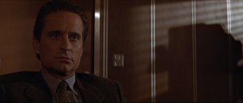 Movie still from “Basic Instinct” (1992), directed by Paul Verhoeven – A man in a suit and tie in a room; Close Up shot, Over the shoulder angle