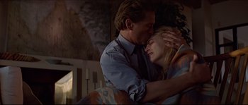 Movie still from “Basic Instinct” (1992), directed by Paul Verhoeven – A man and a woman are kissing on a couch; Medium shot, Low angle