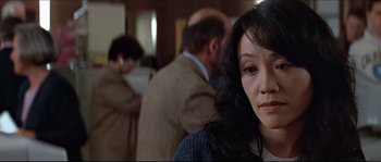 Movie still from “Basic Instinct” (1992), directed by Paul Verhoeven – A person in a room with other people; Close Up shot, Over the shoulder angle