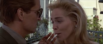 Movie still from “Basic Instinct” (1992), directed by Paul Verhoeven – A man and a woman putting lipstick on each other outside; Close Up shot, Low angle