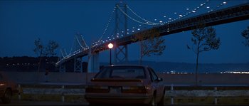Movie still from “Basic Instinct” (1992), directed by Paul Verhoeven – A car parked on the side of the road under a bridge; Extreme Wide shot, Low angle