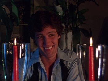 A young man sitting in front of a group of lit candles