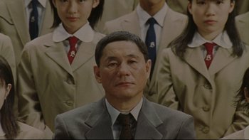 Movie still from “Battle Royale” (2000), directed by Kinji Fukasaku – An older man wearing a suit and tie; Close Up shot, Over the shoulder angle