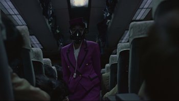 Movie still from “Battle Royale” (2000), directed by Kinji Fukasaku – A person in a purple suit and a hat on a bus; Medium shot, Low angle