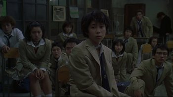 Movie still from “Battle Royale” (2000), directed by Kinji Fukasaku – A group of people sitting in a room; Medium shot, Over the shoulder angle
