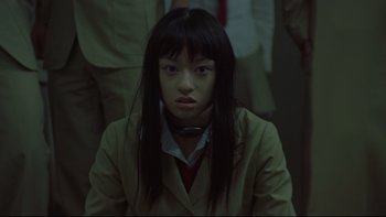 Movie still from “Battle Royale” (2000), directed by Kinji Fukasaku – A woman with long black hair wearing a jacket; Close Up shot, Low angle