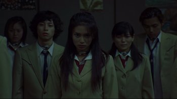 Movie still from “Battle Royale” (2000), directed by Kinji Fukasaku – A group of people standing next to each other in a room; Medium shot, Low angle