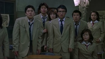 Movie still from “Battle Royale” (2000), directed by Kinji Fukasaku – A group of people in suits and ties standing next to each other in a room; Medium shot, Low angle