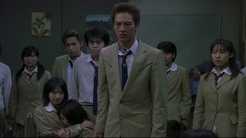 Movie still from “Battle Royale” (2000), directed by Kinji Fukasaku – A group of young men standing next to each other in a room; Medium shot, Low angle