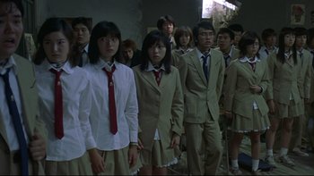 Movie still from “Battle Royale” (2000), directed by Kinji Fukasaku – A group of young people standing together in a room; Medium shot, High angle