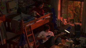 Movie still from “Battle Royale” (2000), directed by Kinji Fukasaku – A man and a woman sitting on top of a bunk bed; Wide shot, High angle