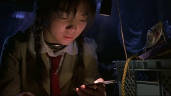 Movie still from “Battle Royale” (2000), directed by Kinji Fukasaku – A girl in a school uniform looking at her cell phone; Close Up shot, Low angle