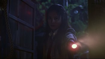Movie still from “Battle Royale” (2000), directed by Kinji Fukasaku – A woman is holding a flashlight in the dark; Medium shot, Low angle