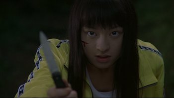 Movie still from “Battle Royale” (2000), directed by Kinji Fukasaku – A woman holding a knife in her hand; Close Up shot, Low angle