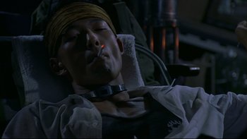 Movie still from “Battle Royale” (2000), directed by Kinji Fukasaku – A man is laying in a chair and smoking a cigarette; Close Up shot, High angle