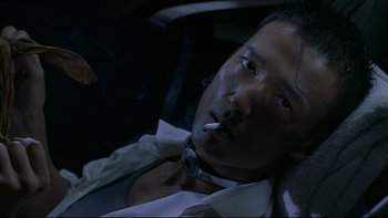 Movie still from “Battle Royale” (2000), directed by Kinji Fukasaku – A man smoking a cigarette while sitting in a car; Close Up shot, High angle