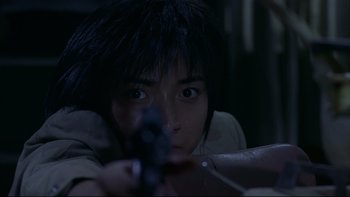 Movie still from “Battle Royale” (2000), directed by Kinji Fukasaku – A young person holding a gun in a dark room; Close Up shot, Low angle
