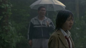 Movie still from “Battle Royale” (2000), directed by Kinji Fukasaku – A man holding an umbrella in front of a woman; Medium shot, Over the shoulder angle