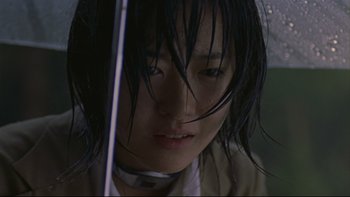 Movie still from “Battle Royale” (2000), directed by Kinji Fukasaku – A young woman with long black hair holding an umbrella in the dark; Close Up shot, Low angle