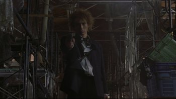 Movie still from “Battle Royale” (2000), directed by Kinji Fukasaku – A man in a suit and tie pointing at the camera; Medium shot, Low angle