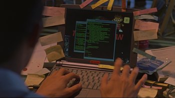 Movie still from “Battle Royale” (2000), directed by Kinji Fukasaku – A person using a laptop on a desk covered in sticky notes; Close Up shot, High angle