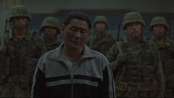 Movie still from “Battle Royale” (2000), directed by Kinji Fukasaku – A group of soldiers standing next to each other; Medium shot, Over the shoulder angle