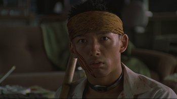 Movie still from “Battle Royale” (2000), directed by Kinji Fukasaku – A man with a bandage on his head holding a baseball bat; Close Up shot, Low angle